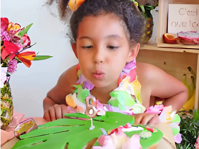 Enfant soufflant les bougies lors d’un anniversaire Vaiana à domicile avec décoration tropicale